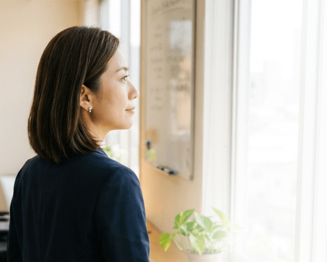 窓から光が差すオフィスで、穏やかに振り向く人事担当の女性