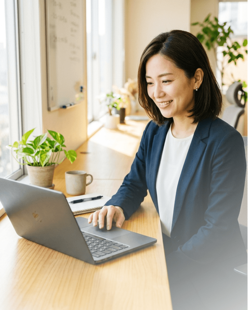 明るいオフィスでノートPCの画面を見て微笑む、人事担当の女性